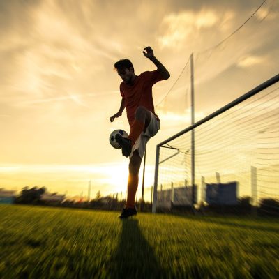 Silhouette of a soccer player on a football field at sunset. Silhouette of a soccer player on a football field at sunset.