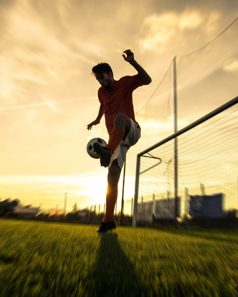 Silhouette of a soccer player on a football field at sunset. Silhouette of a soccer player on a football field at sunset.